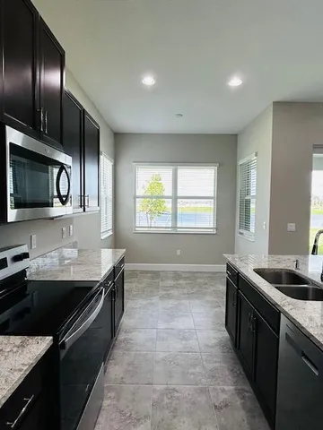 a kitchen with granite countertop stainless steel appliances a sink stove top oven and cabinets