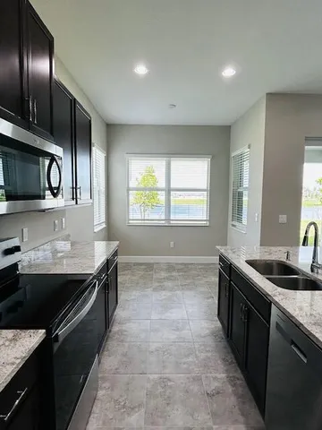 a kitchen with granite countertop stainless steel appliances a sink stove top oven and cabinets