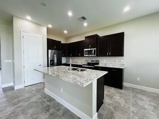 a kitchen with stainless steel appliances granite countertop a stove top oven a sink and a refrigerator