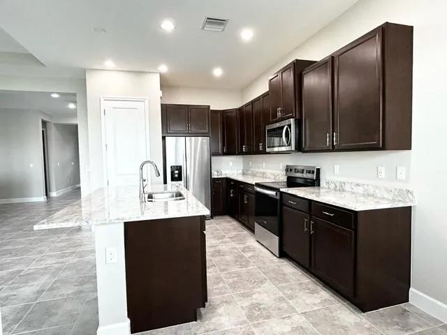 a kitchen with kitchen island granite countertop wooden cabinets a refrigerator and a sink