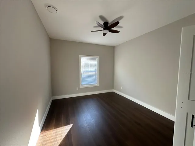 a view of an empty room with wooden floor and a window