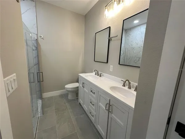 a spacious bathroom with a double vanity sink toilet mirror and shower