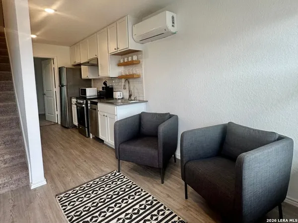 a living room with stainless steel appliances furniture a couch and a stove top oven