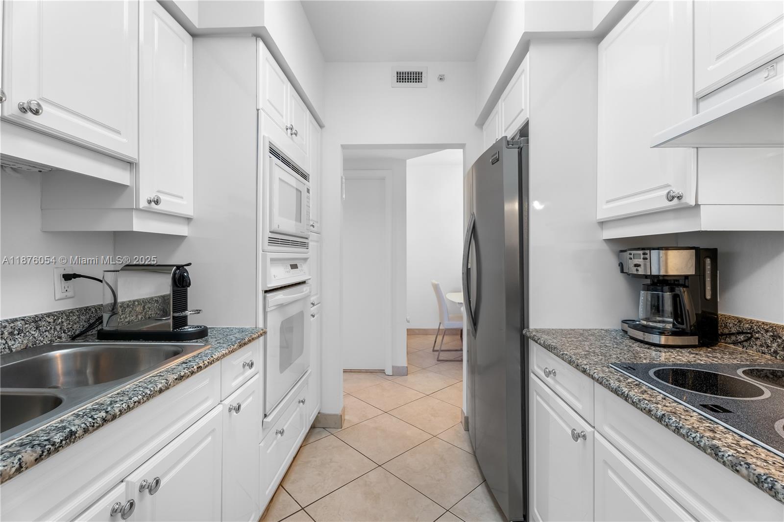 4779 Collins Avenue, Unit 1008 Miami Beach, FL 33140 - Photo 10 of 36 a kitchen with stainless steel appliances granite countertop a sink and a refrigerator