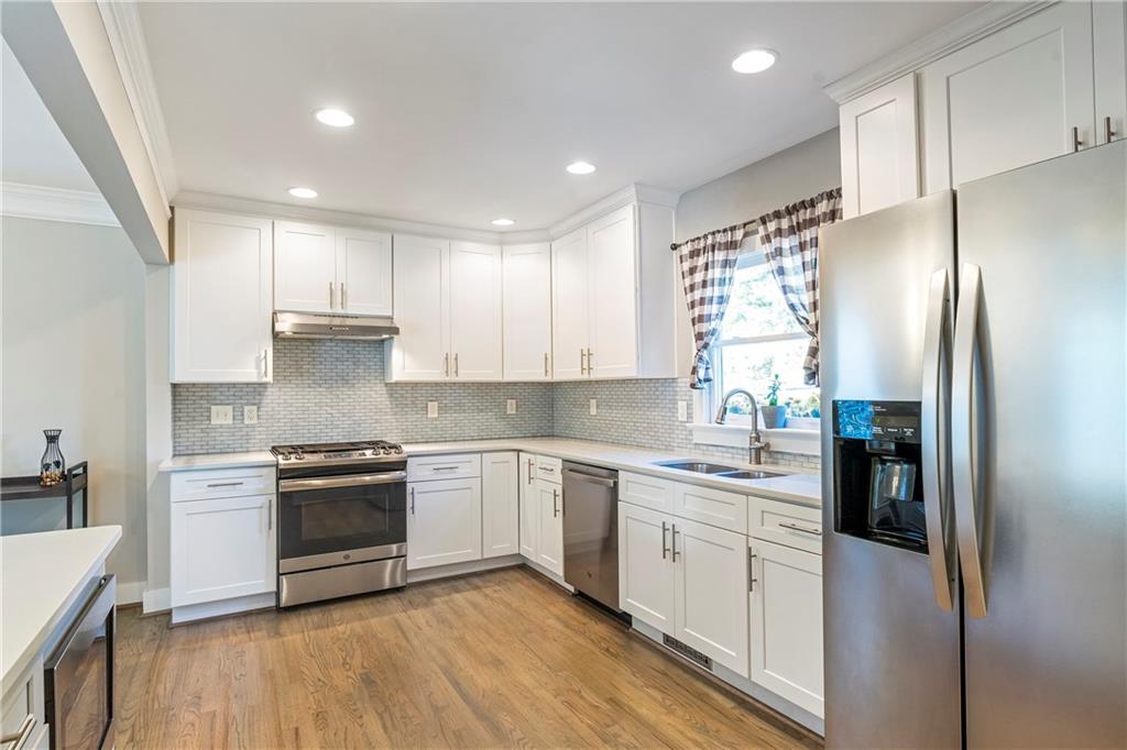 1403 Lavista Road Northeast Atlanta, GA 30324 - Photo 9 of 43 a kitchen with stainless steel appliances granite countertop a refrigerator a sink a stove and white cabinets with wooden floor