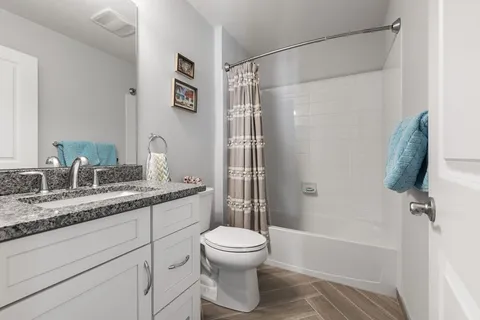 a bathroom with a granite countertop sink toilet and shower