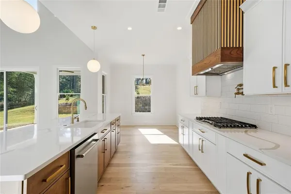a view of an empty room with wooden floor staircase and a kitchen view