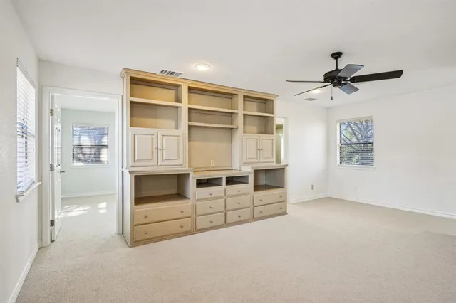 an empty room with windows and a ceiling fan