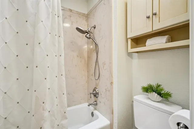 a bathroom with a shower curtain a sink and a toilet