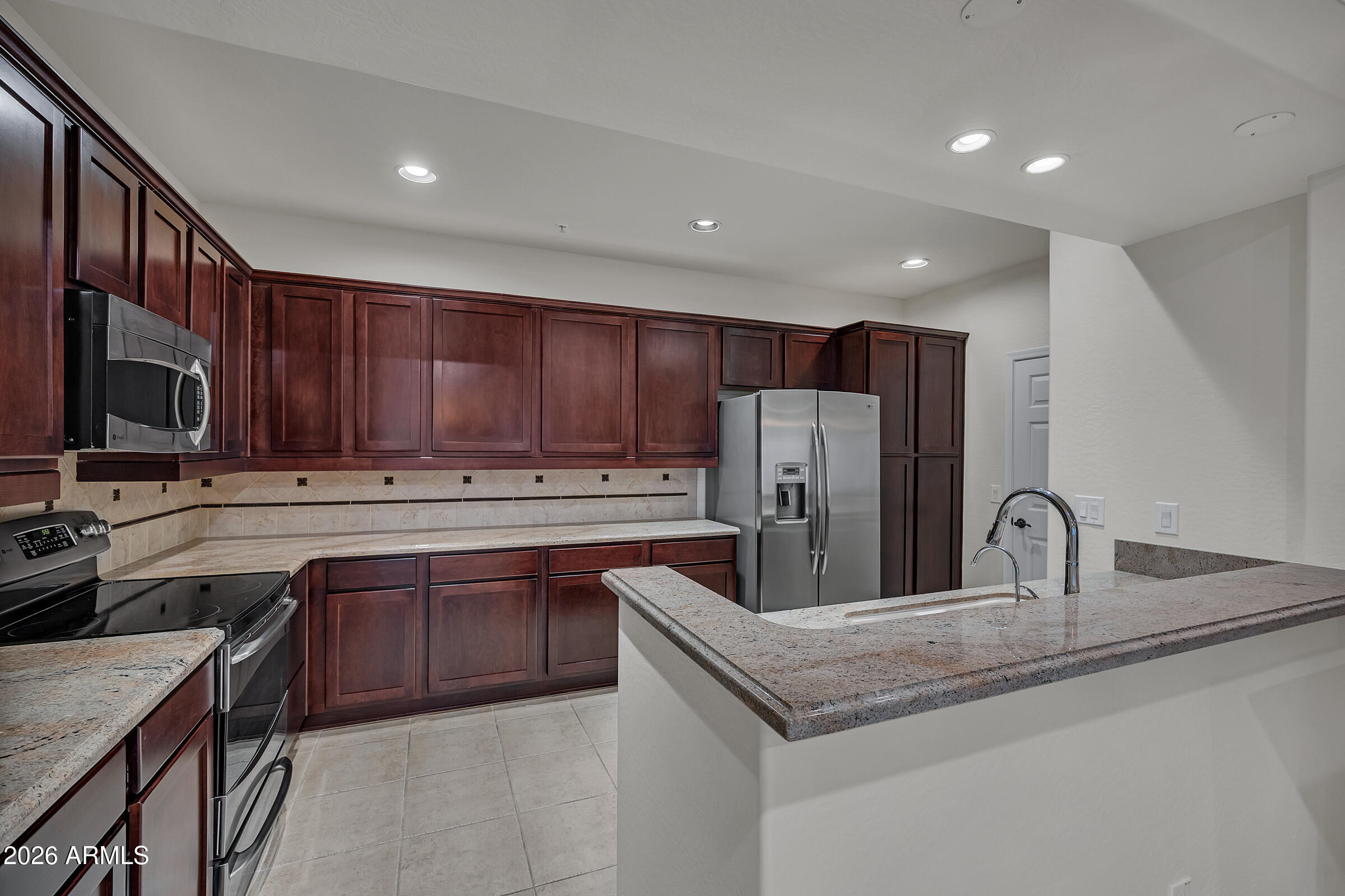 3935 East Rough Rider Road, Unit 1250 Phoenix, AZ 85050 - Photo 9 of 29 a kitchen with stainless steel appliances granite countertop a sink stove and refrigerator