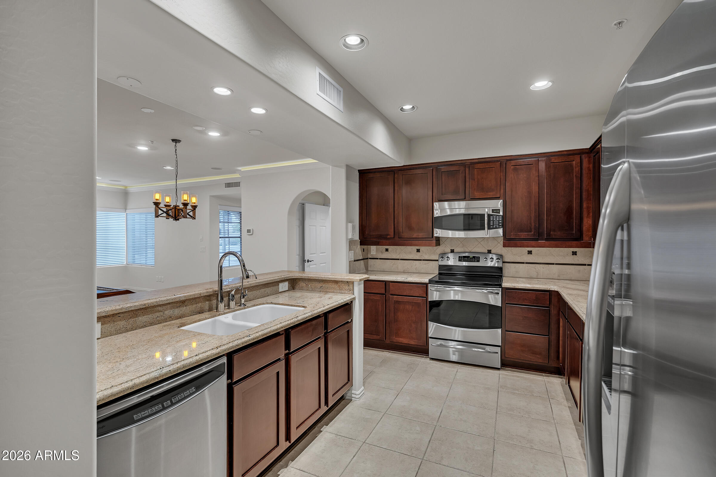 3935 East Rough Rider Road, Unit 1250 Phoenix, AZ 85050 - Photo 10 of 29 a kitchen with granite countertop stainless steel appliances and wooden cabinets