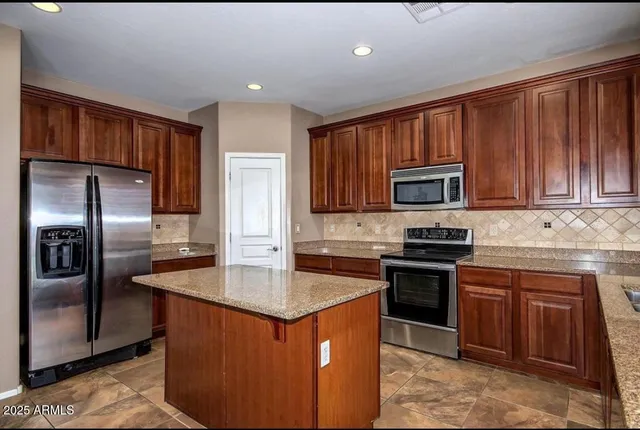 a kitchen with stainless steel appliances granite countertop a stove a sink dishwasher a refrigerator and a microwave oven