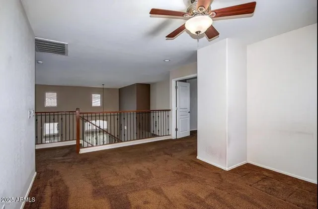 an empty room with ceiling fan and windows