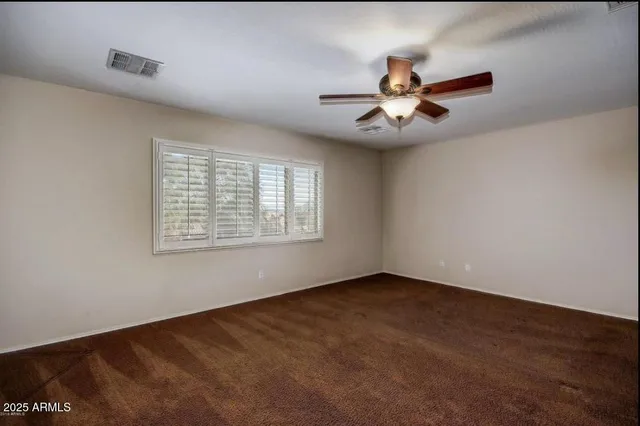 an empty room with windows and fan