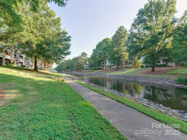 a view of a lake with a big yard and large trees