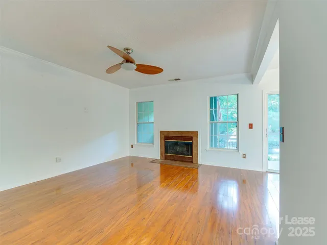 an empty room with windows fireplace and wooden floor