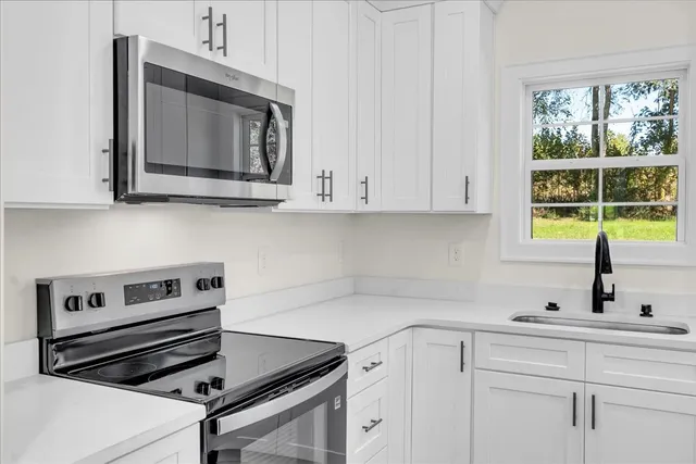 a kitchen with white cabinets and appliances