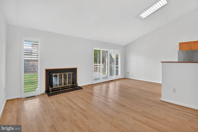 a view of wooden floor fire place and windows in an empty room