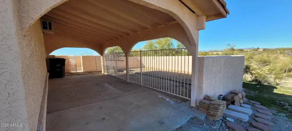 a view of a patio with a table and chairs under an umbrella with a small yard