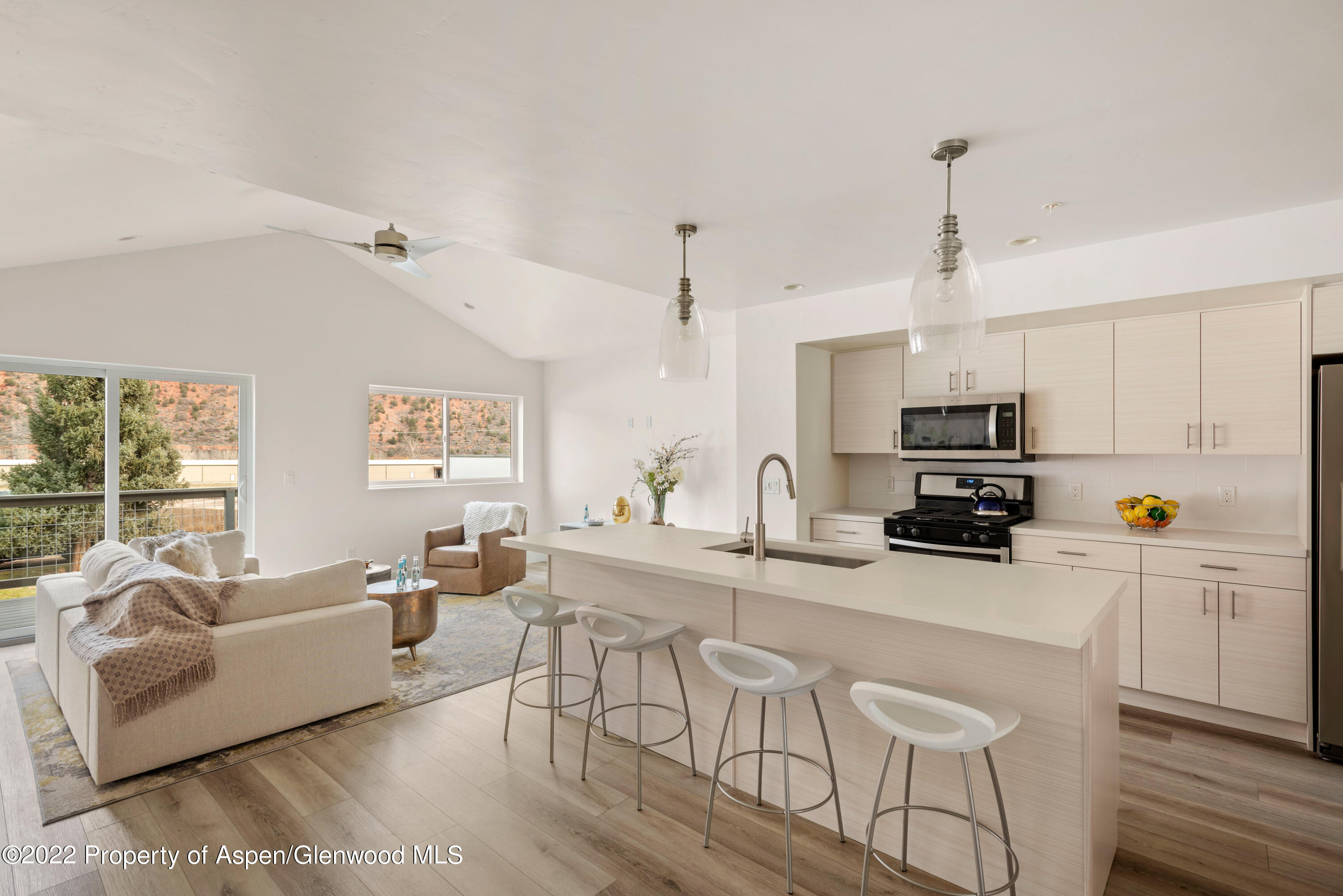 a kitchen with stainless steel appliances kitchen island granite countertop a stove a sink a dining table and chairs with wooden floor