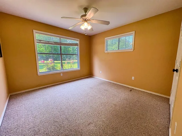 an empty room with windows and ceiling fan