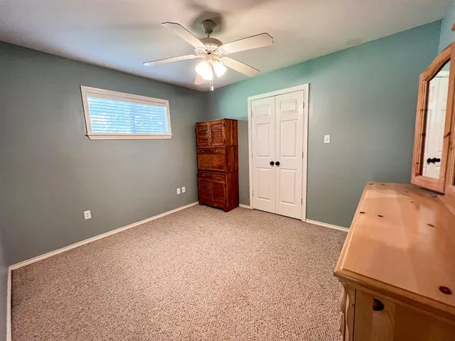 an empty room with a window and a ceiling fan