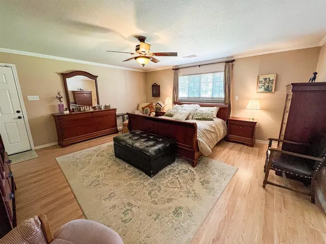 a large bedroom with a bed and wooden floor