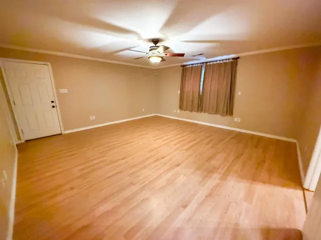 a view of an empty room with window and wooden floor