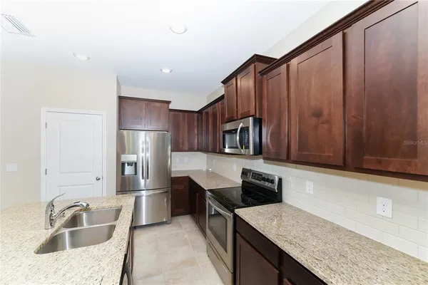 a kitchen with stainless steel appliances granite countertop a sink refrigerator and microwave