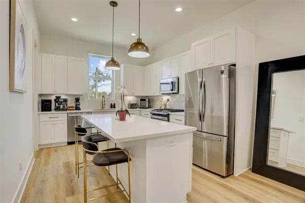 a kitchen with a refrigerator a stove and white cabinets with wooden floor