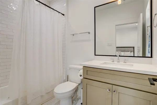 a bathroom with a granite countertop sink vanity mirror and toilet