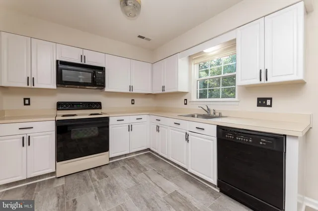 a kitchen with granite countertop white cabinets and stainless steel appliances
