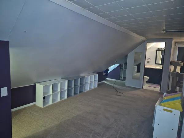 a view of an empty room with wooden floor and a sink