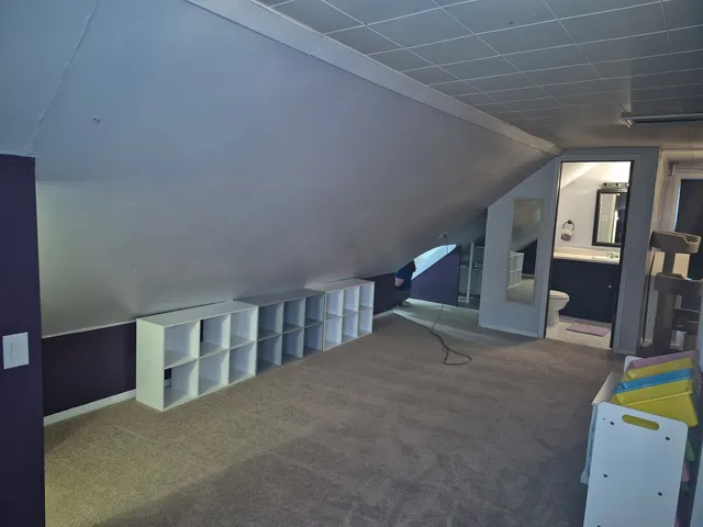 a view of an empty room with wooden floor and a sink