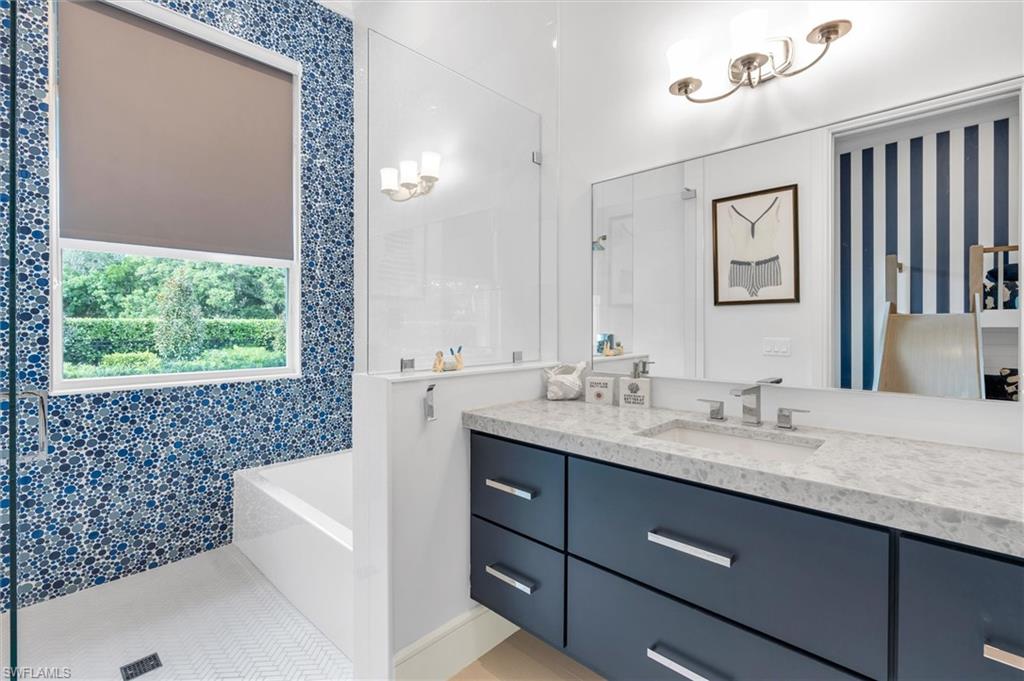830 Cassena Road Naples, FL 34108 - Photo 20 of 41 a bathroom with a granite countertop sink a large mirror a bathtub and window