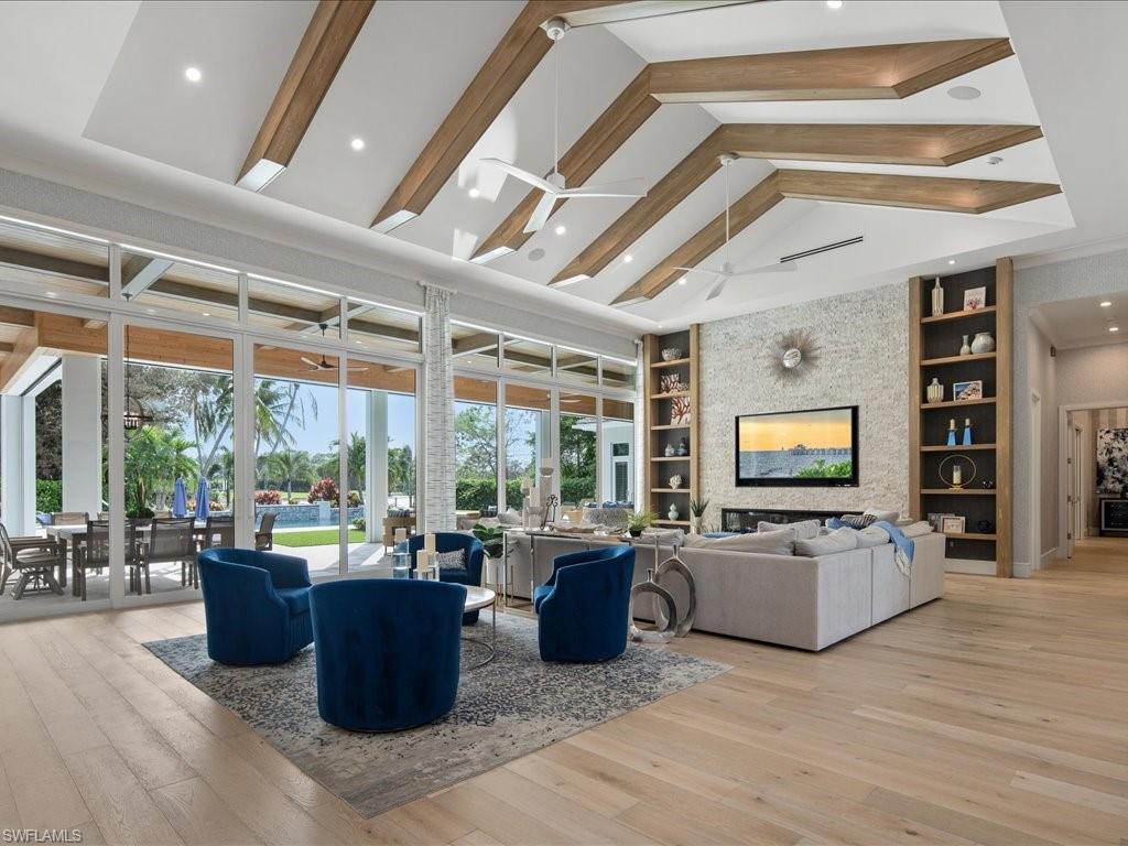 830 Cassena Road Naples, FL 34108 - Photo 3 of 41 a living room with furniture a flat screen tv and floor to ceiling windows