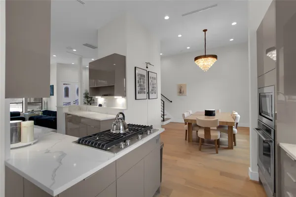a kitchen with stainless steel appliances granite countertop a stove top oven a sink dishwasher a dining table and chairs with wooden floor