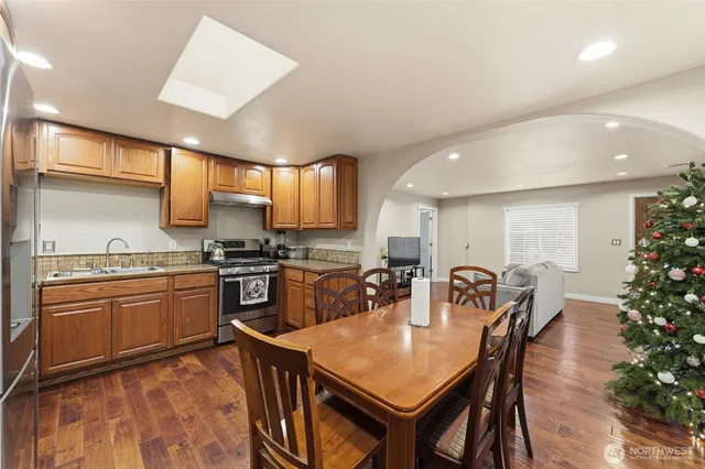 a kitchen with granite countertop a table chairs stove a sink and dishwasher