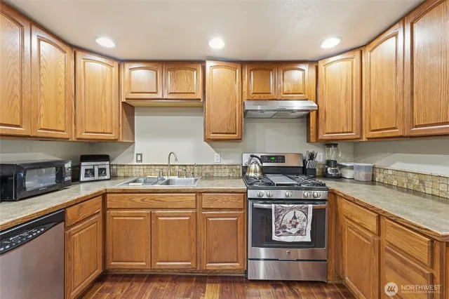 a kitchen with stainless steel appliances granite countertop a stove sink and cabinets