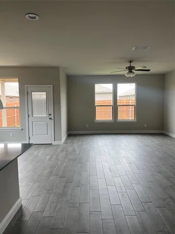 an empty room with windows and chandelier fan