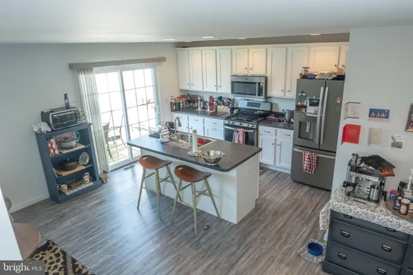 a kitchen with stainless steel appliances a stove a sink dishwasher a refrigerator with a dining table and chairs with wooden floor