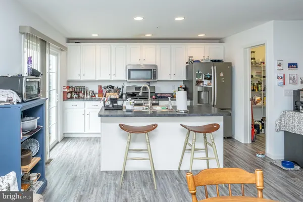 a kitchen with stainless steel appliances granite countertop a refrigerator a stove top oven and a dining table with wooden floor