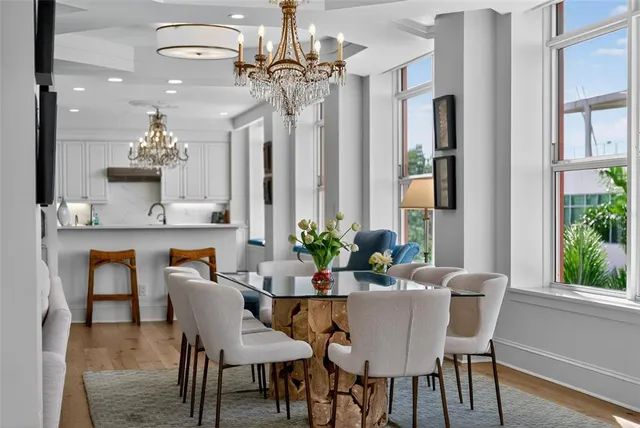 a view of a dining room with furniture a chandelier and large windows
