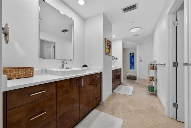a bathroom with a granite countertop double vanity sink mirror bathtub and toilet