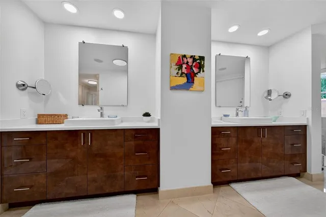 a white bed sitting in a bedroom next to a window with a chandelier
