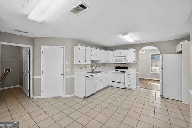 a kitchen with white cabinets a sink and appliances