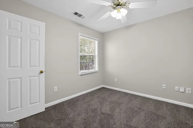 an empty room with windows and fan