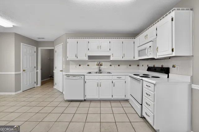 a kitchen with granite countertop white cabinets and white appliances
