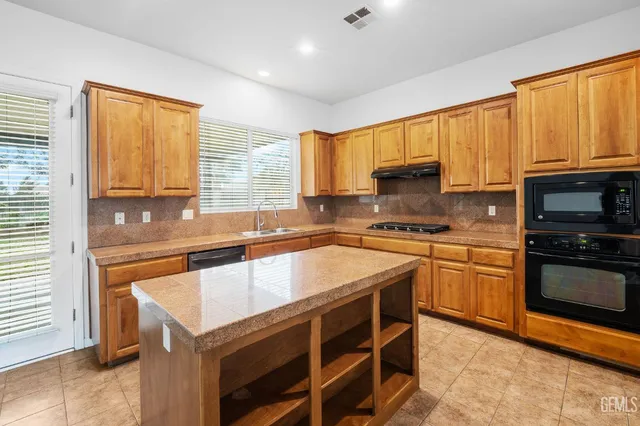 a kitchen with stainless steel appliances granite countertop a stove a sink dishwasher a microwave oven and a refrigerator with wooden cabinets