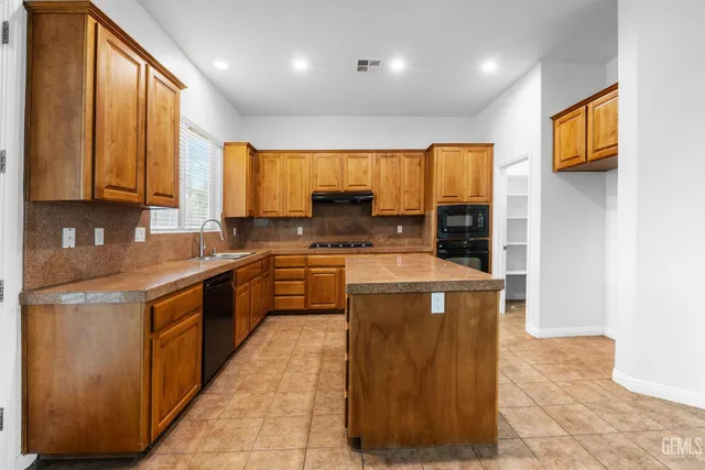 a kitchen with stainless steel appliances granite countertop wooden cabinets a stove top oven a sink and dishwasher